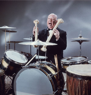 Alfred Hitchcock playfully plays the drums with femurs as drumsticks.